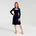Woman in navy long sleeve dress in white room 