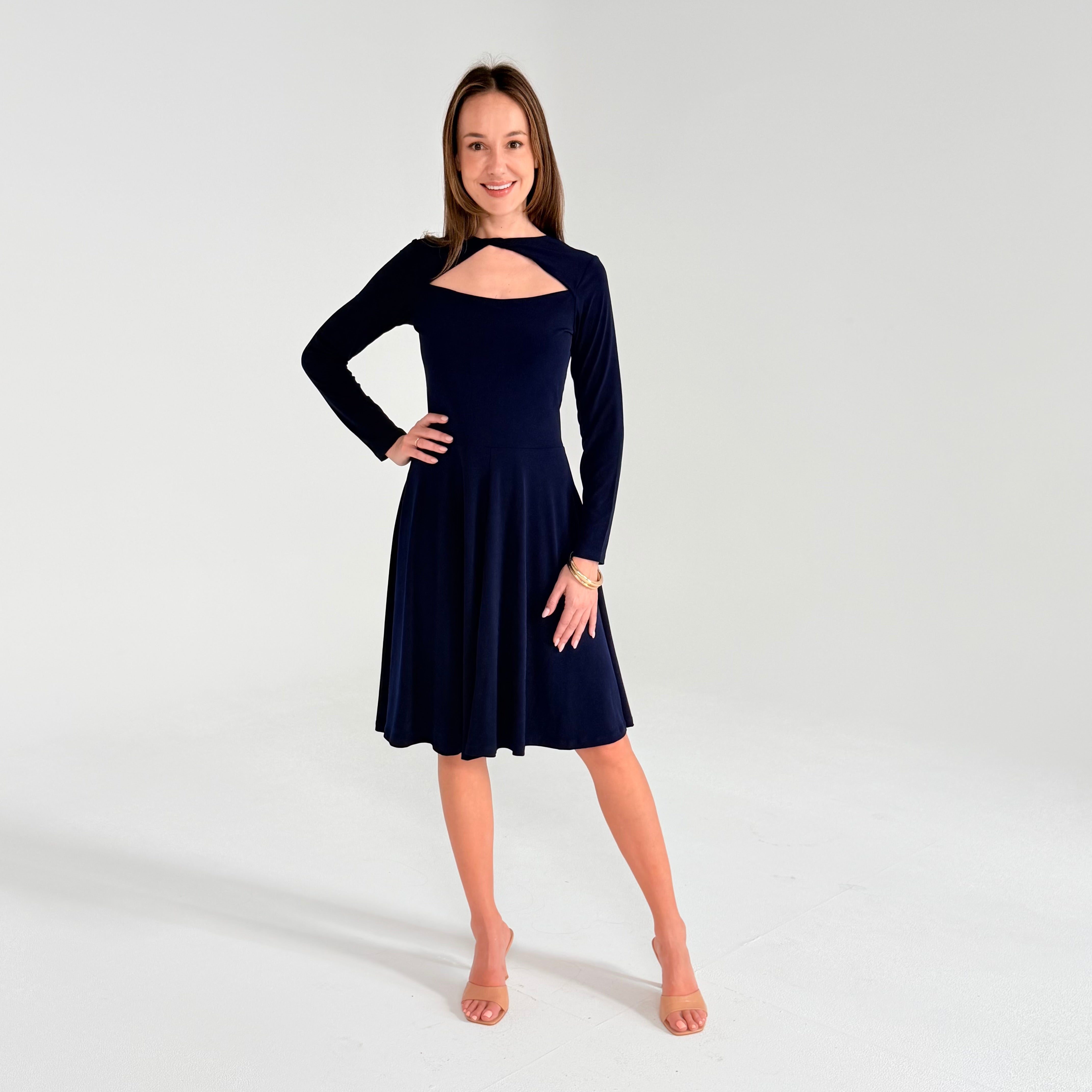 Woman in navy long sleeve dress in white room 