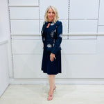Penelope dress in deep navy blue, worn by model- elegant long sleeve design, knee length, with modern neckline, worn with Navy blue & white embroidered silk jacket, designed and Made in Australia.