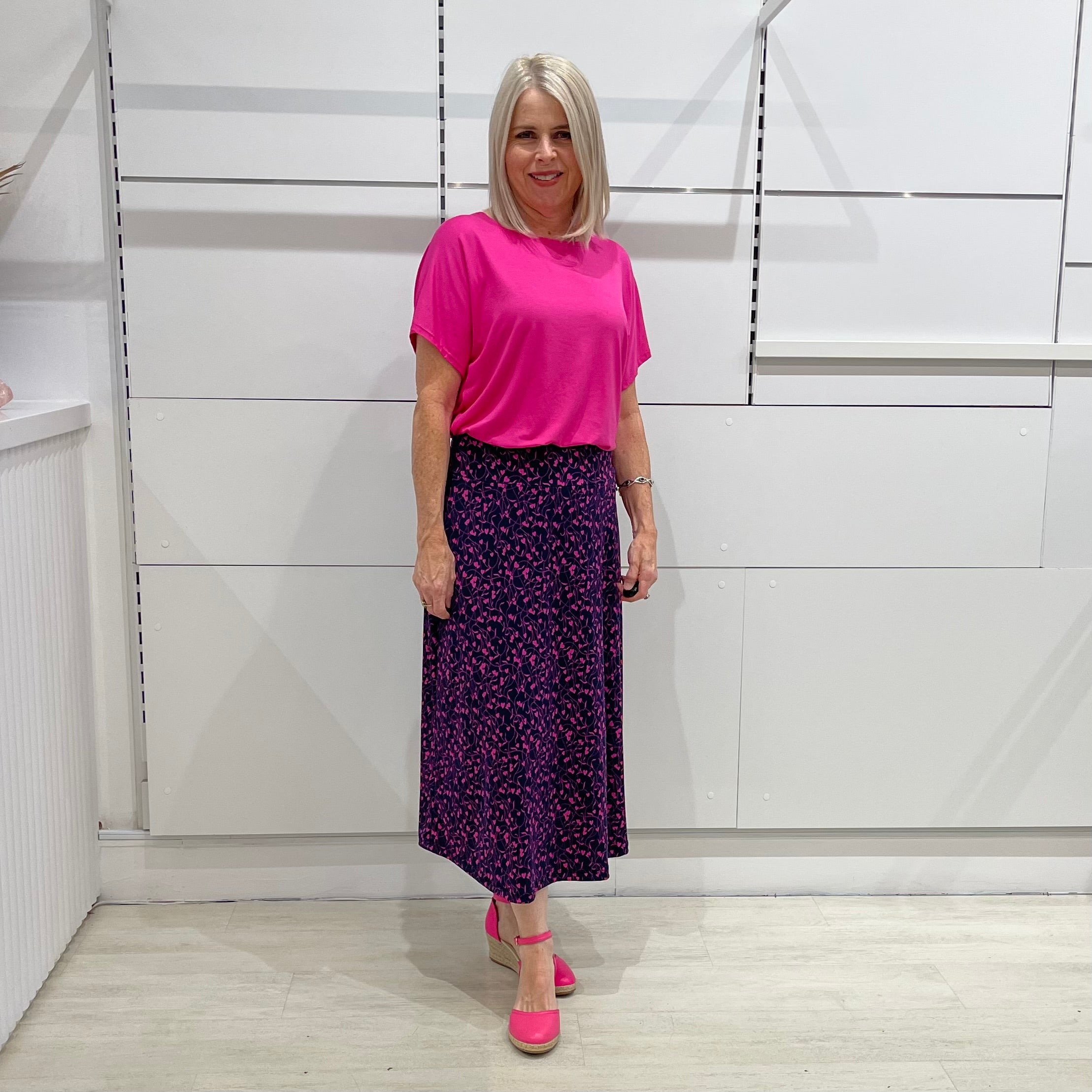 Maxi, long skirt, navy colour with small pink heart pattern. Stretch elastic waistband. Worn with hot pink short sleeve, round neck top.