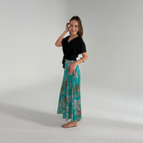 Woman wearing a black top and teal floral skirt on a gray background