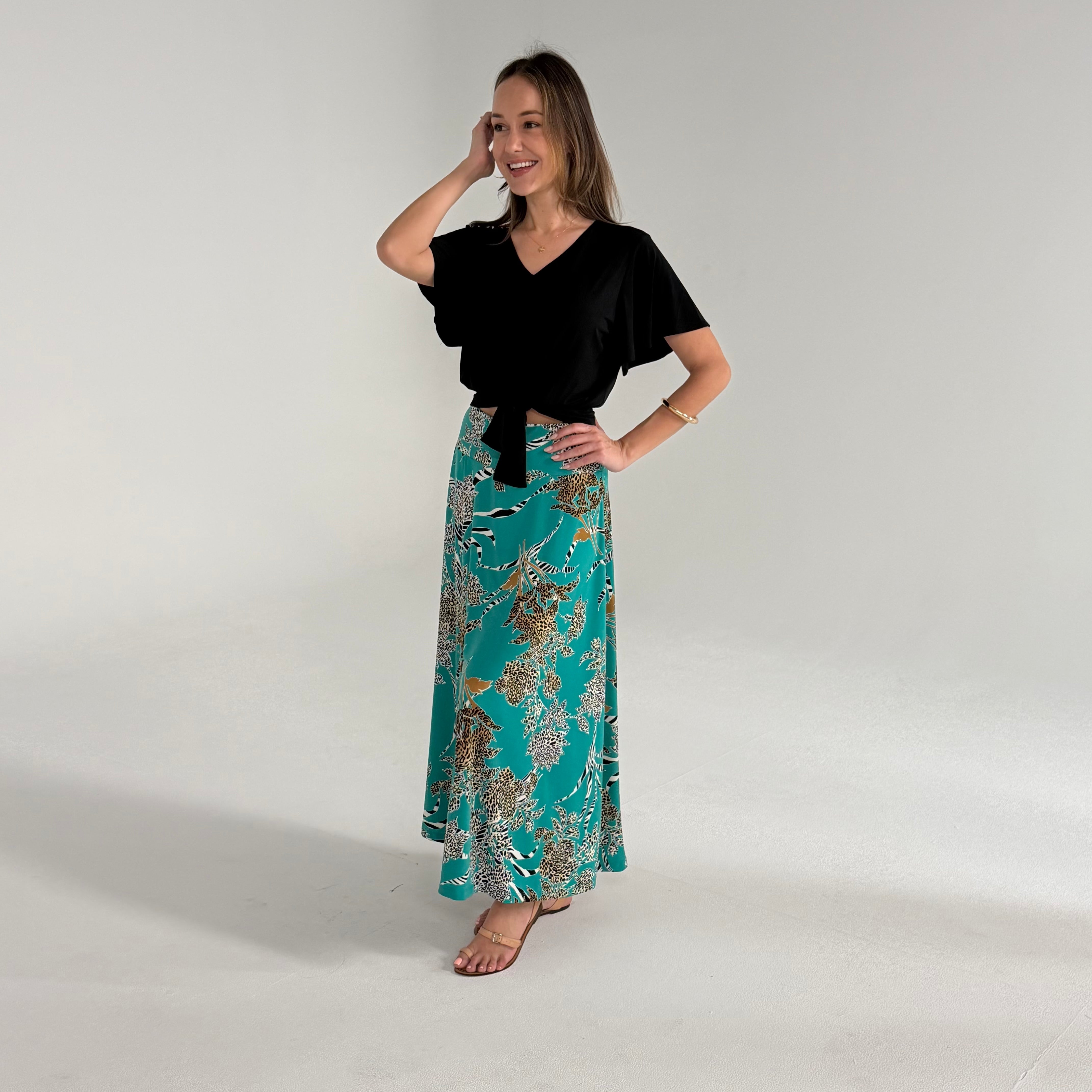 Woman wearing a black top and teal floral skirt on a white background