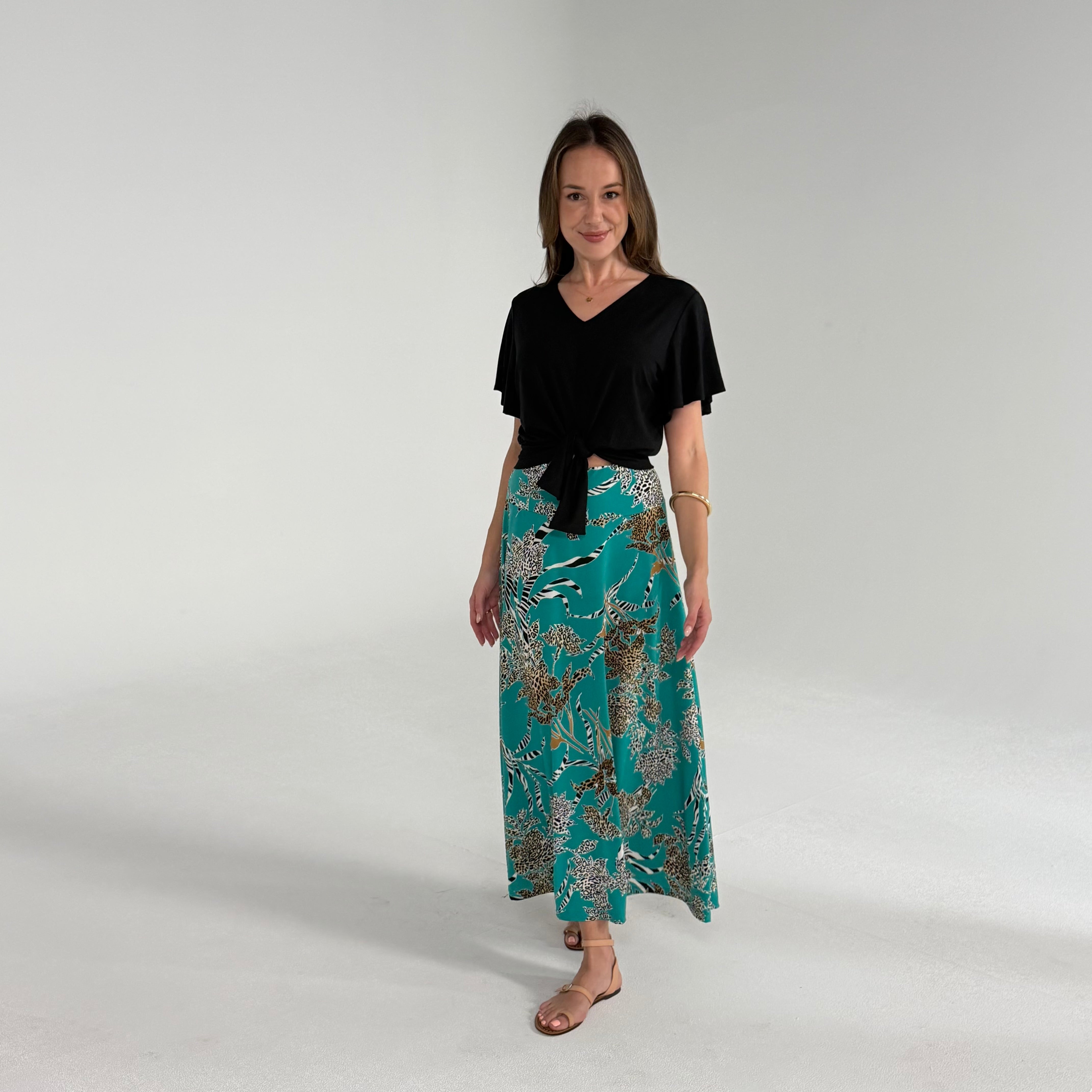 Woman wearing a black top and patterned skirt on a plain background