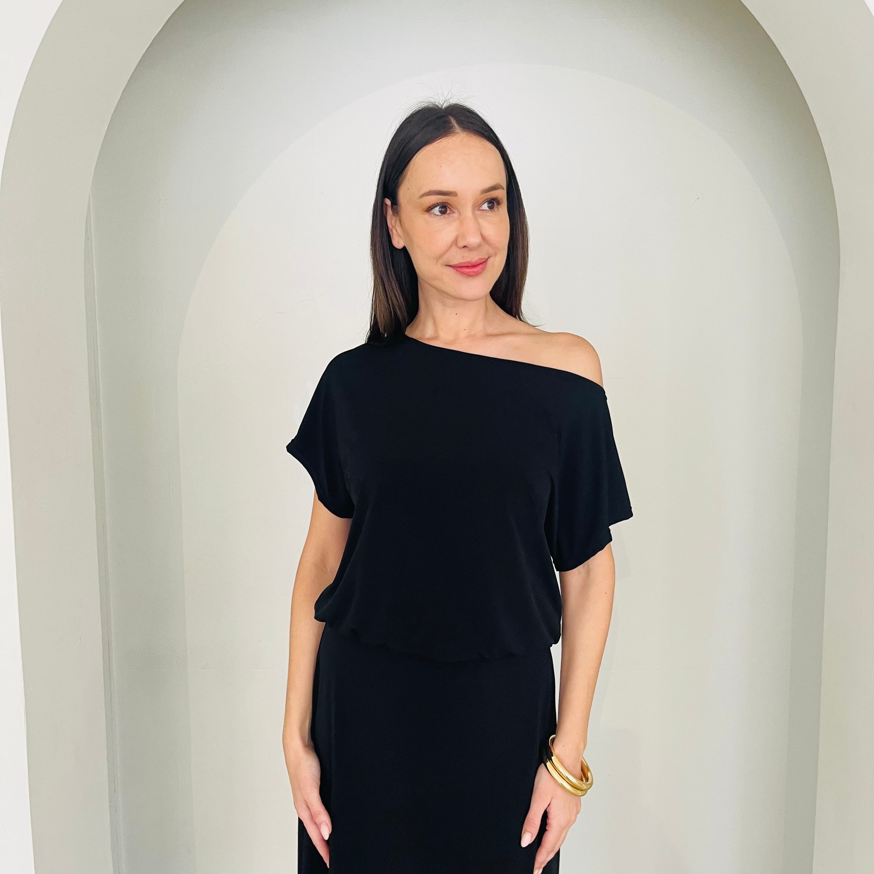 Woman wearing a black off-shoulder top and skirt against a neutral background