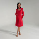 Woman wearing an orange dress with long sleeves on a plain background