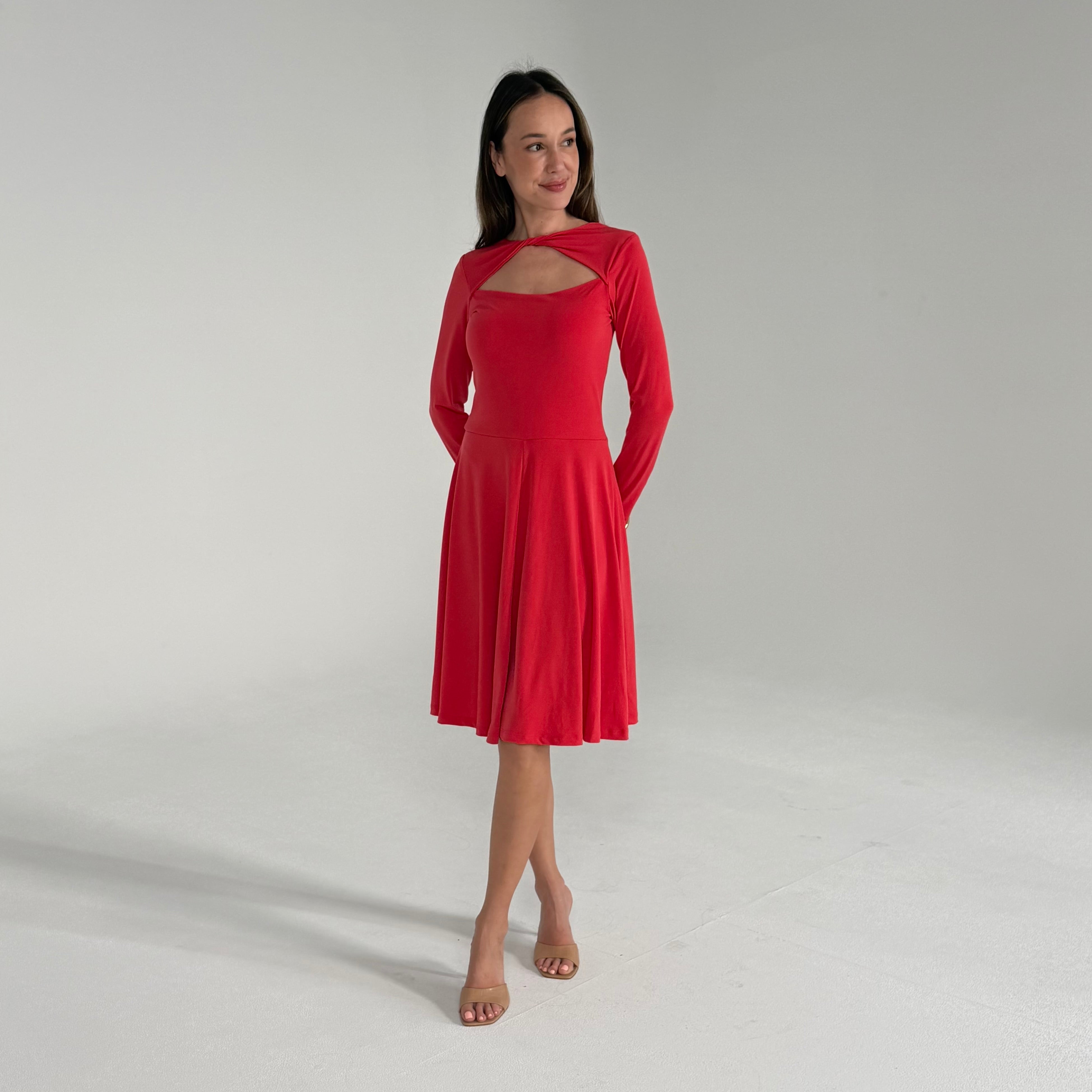 Woman wearing an orange dress with long sleeves on a plain background