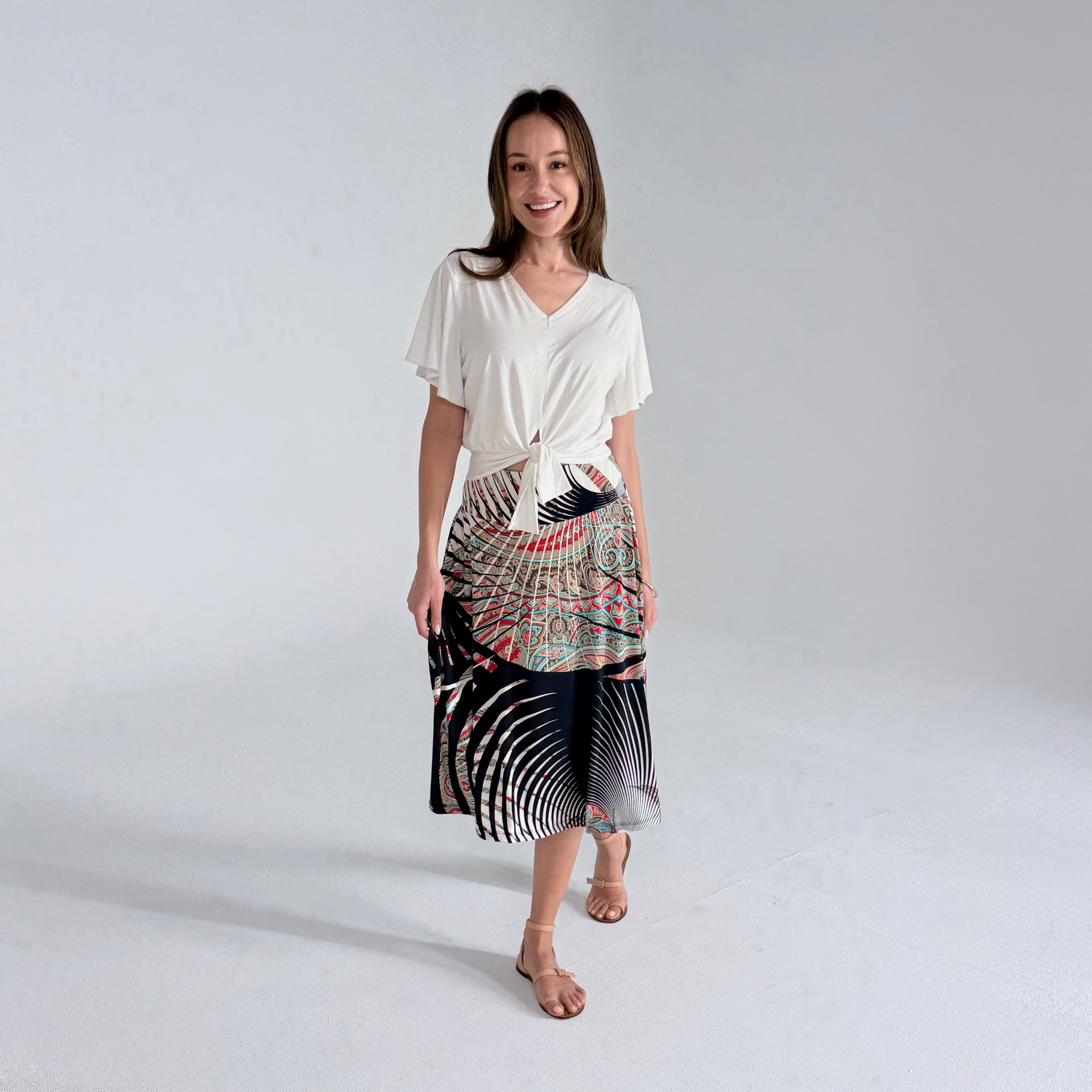 Woman wearing a white top and patterned skirt on a white background