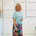 Woman wearing a light blue top and colorful skirt against a white background
