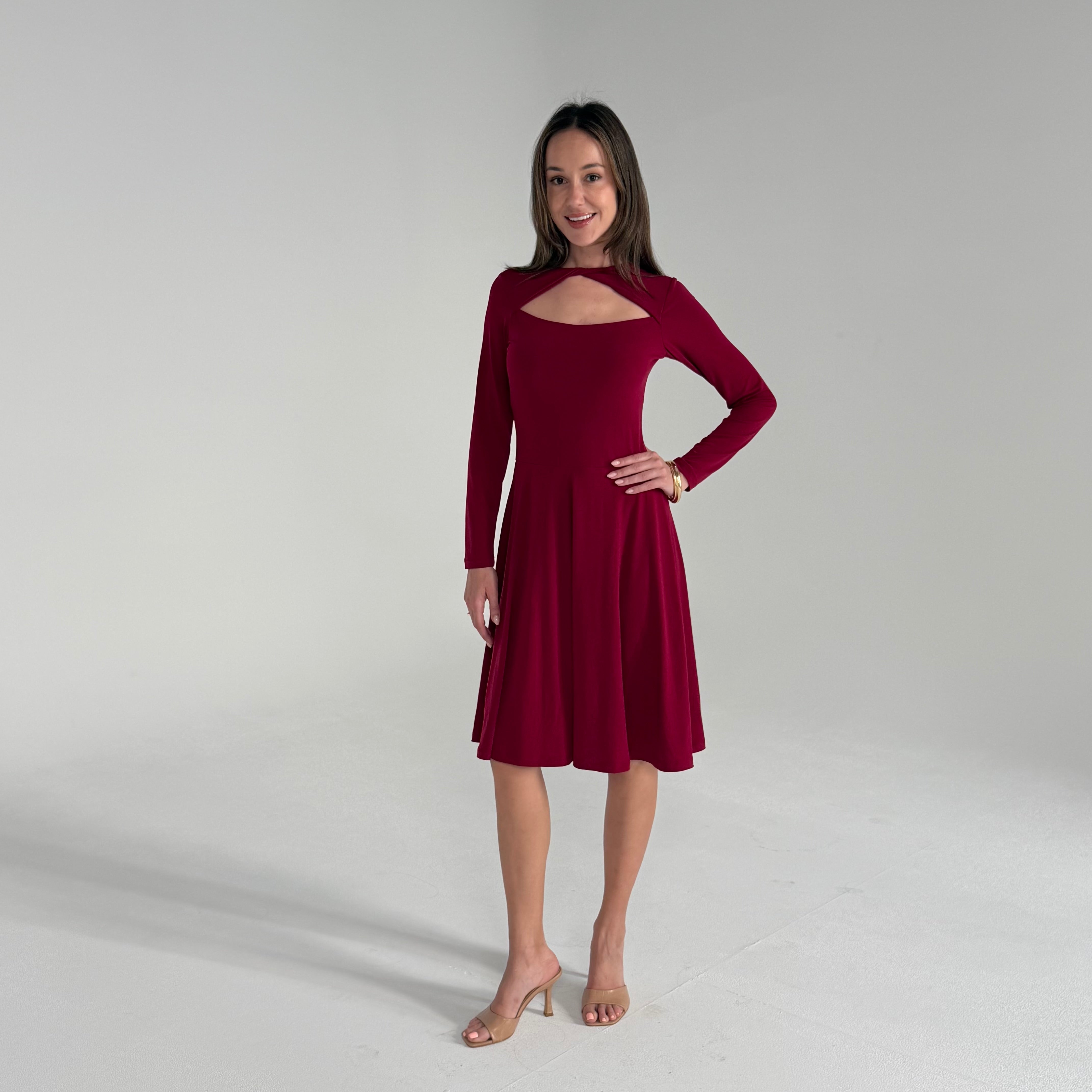 Woman wearing a burgundy dress with long sleeves on a plain background