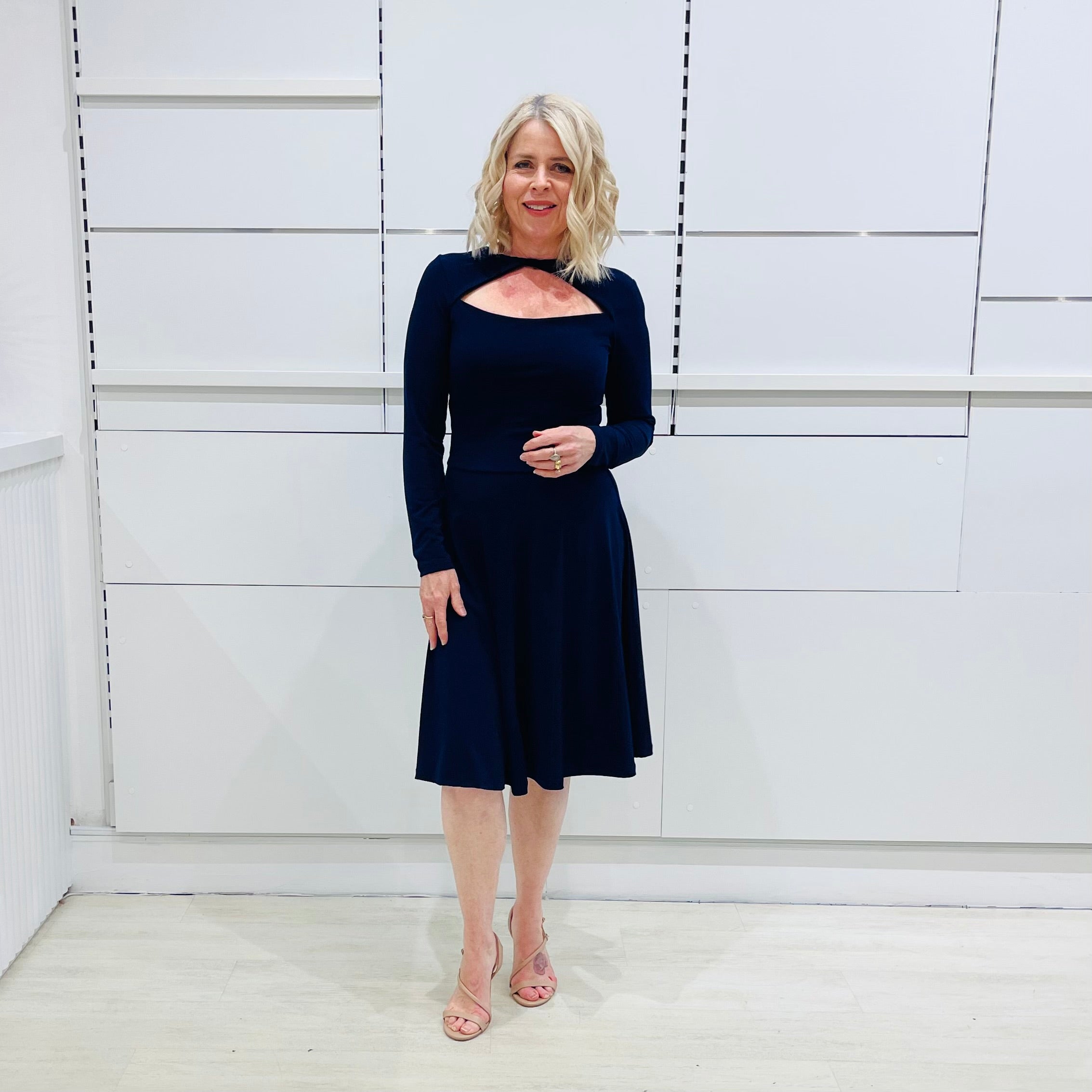 Penelope dress in deep navy blue, worn by model- elegant long sleeve design, knee length, with modern neckline.