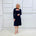 Penelope dress in deep navy blue, worn by model- elegant long sleeve design, knee length, with modern neckline.