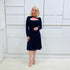 Penelope dress in deep navy blue, worn by model- elegant long sleeve design, knee length, with modern neckline.