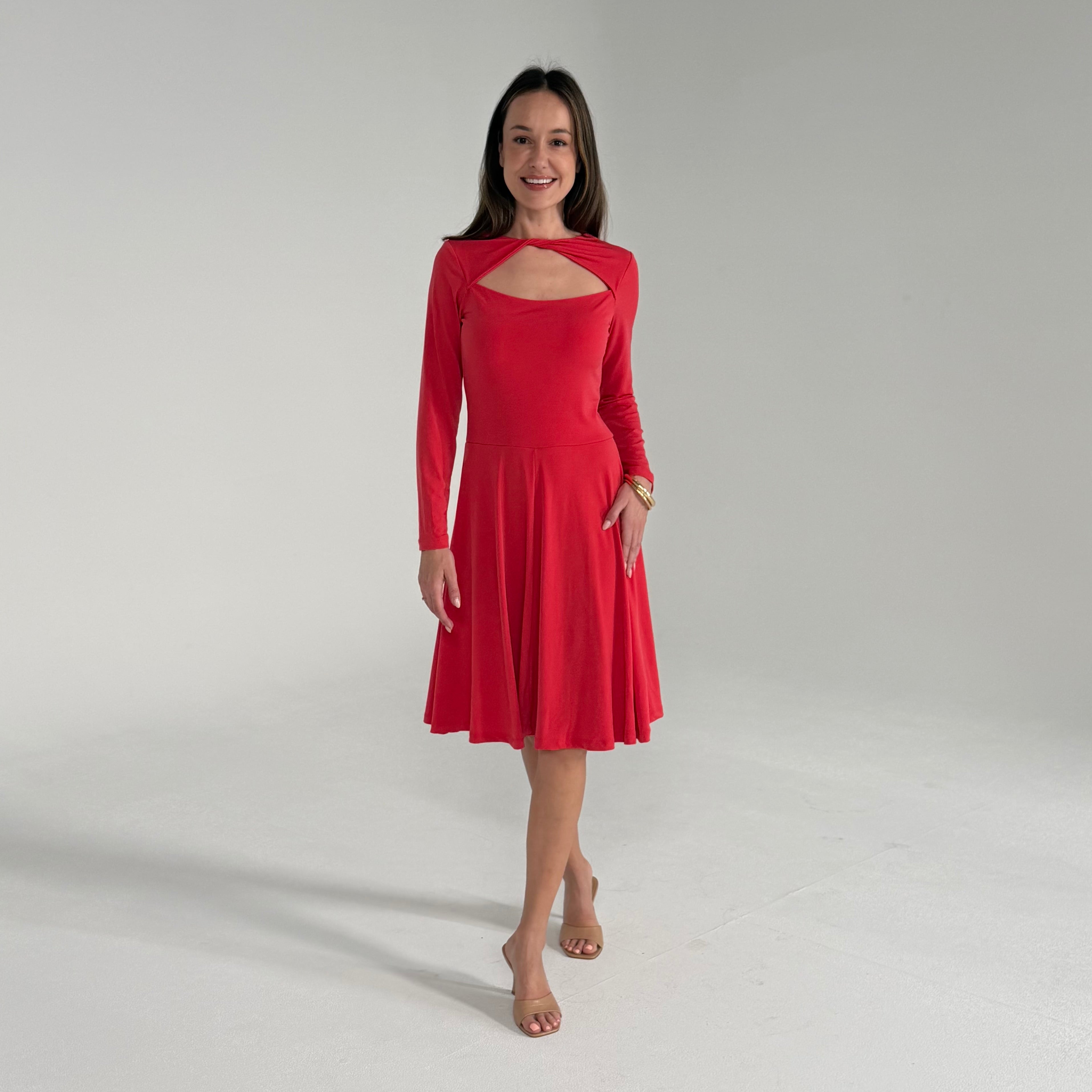 Woman wearing a red dress with a cutout design on a plain background