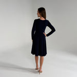 Woman wearing Navy Blue Dress  standing in white room 
