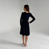 Woman wearing Navy Blue Dress  standing in white room 