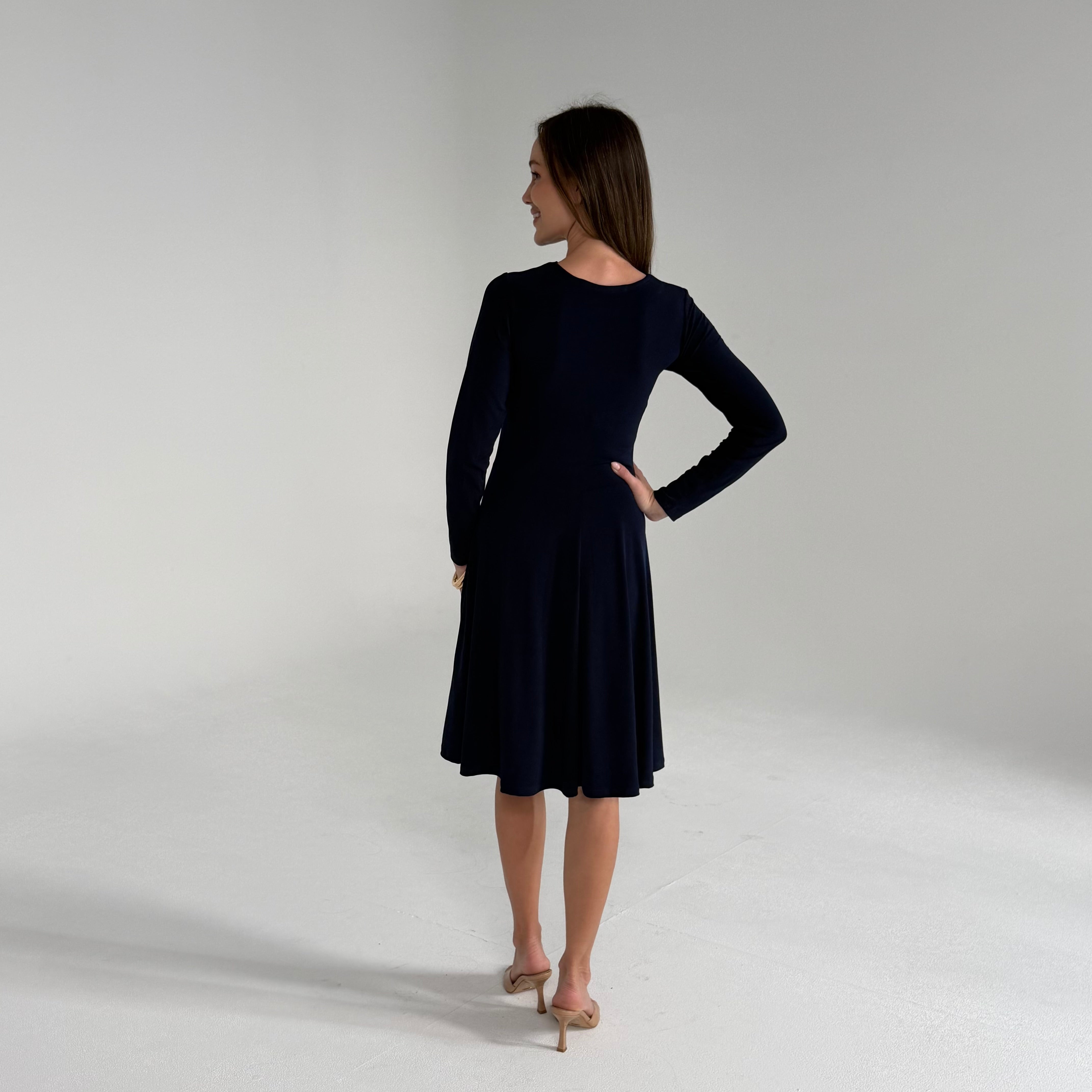 Woman wearing Navy Blue Dress  standing in white room 