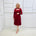 Woman wearing the Penelope dress n rich ruby red, featuring a fit-and-flare, knee length, slihouette, full length sleeves, and a cut out neckline.