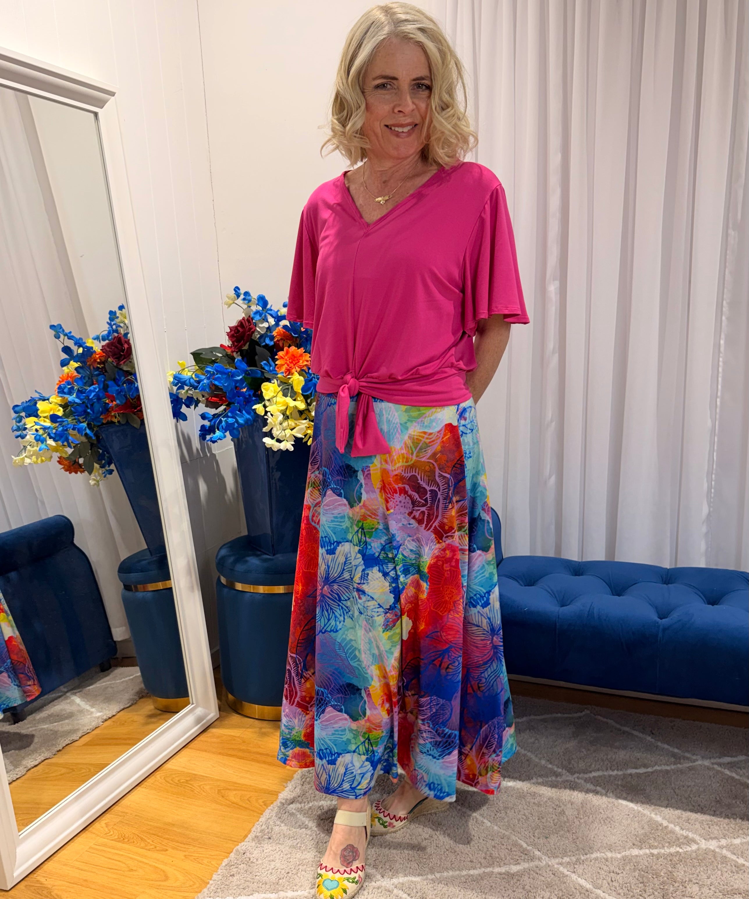 Woman wearing pink short sleeve top and colourful skirt.