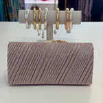 Sparkly clutch bag with a display of earrings on a white surface