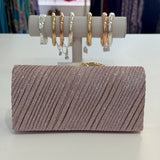 Sparkly clutch bag with a display of earrings on a white surface