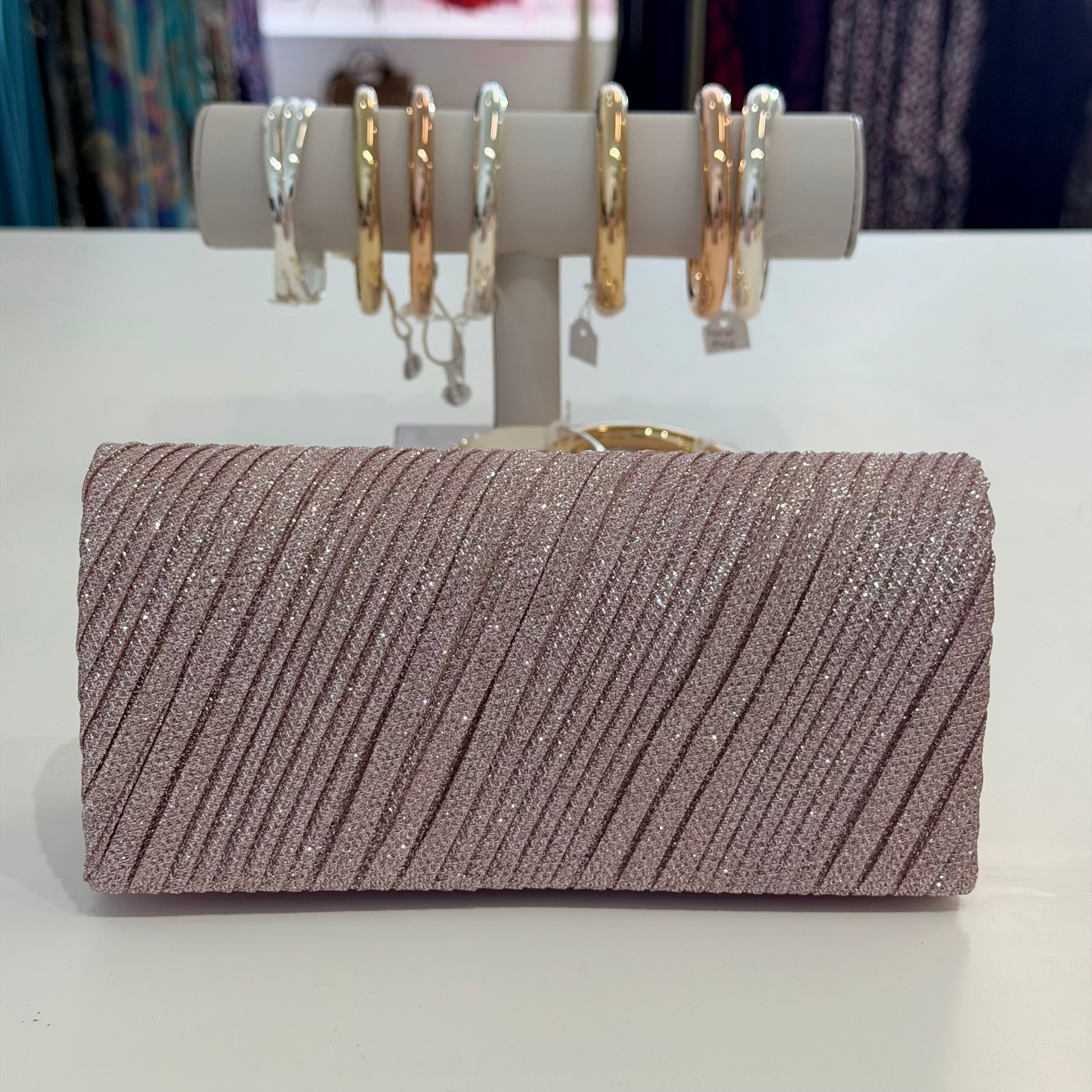 Sparkly clutch bag with a display of earrings on a white surface
