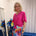 Woman wearing pink short sleeve top and colourful skirt.