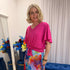 Woman wearing pink short sleeve top and colourful skirt.