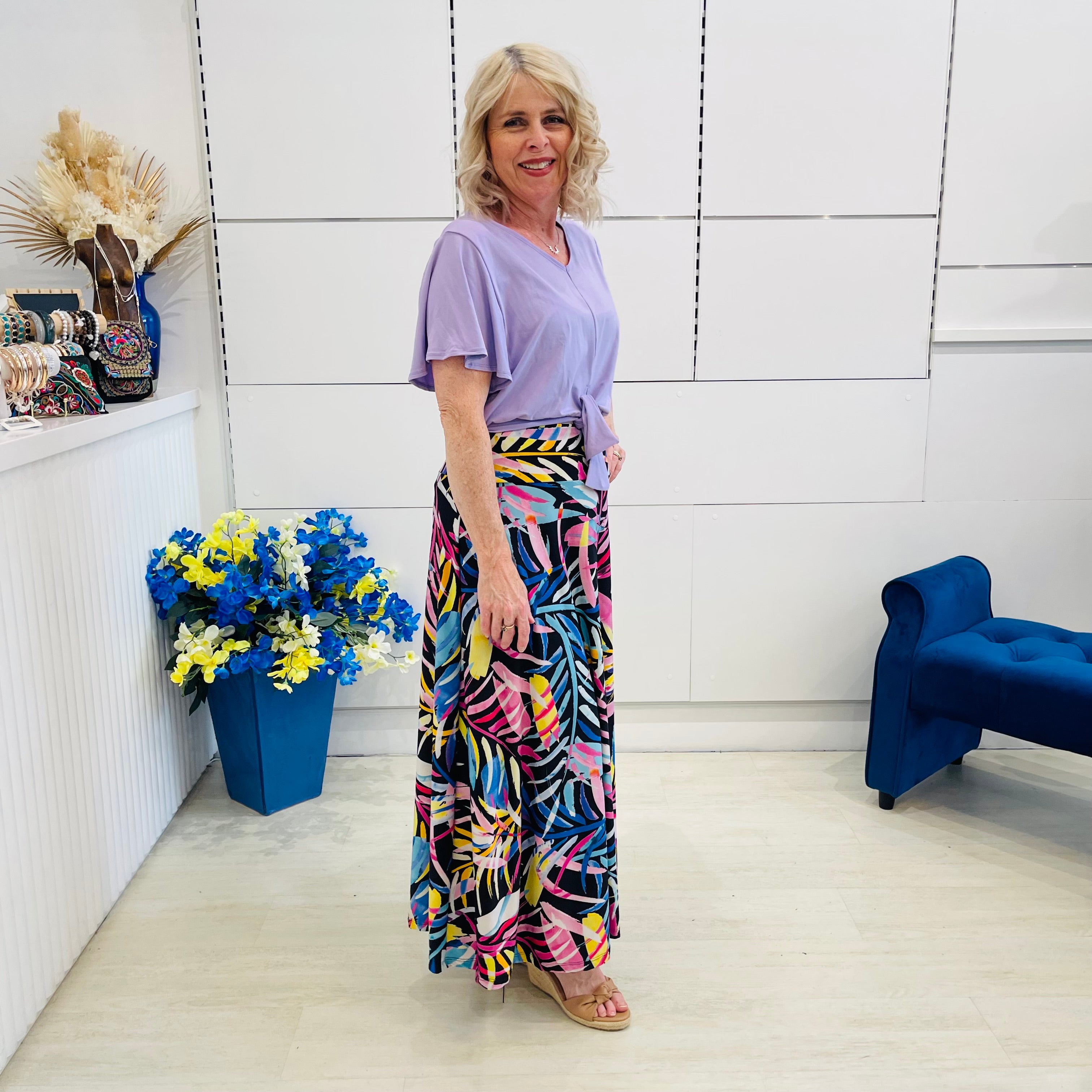 Woman in a colorful outfit standing in a room with decorative elements.