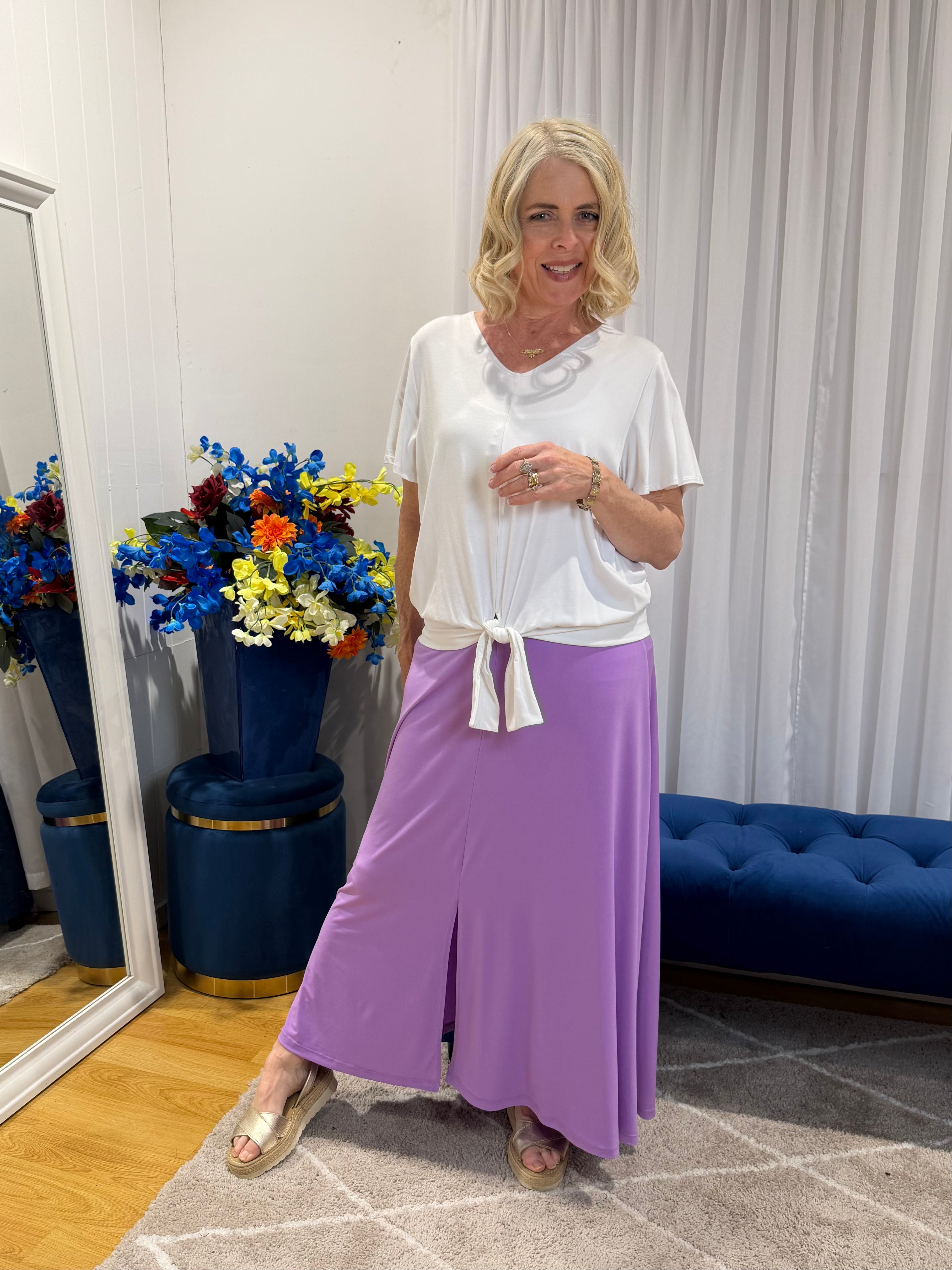 Woman wearing white top and purple skirt 