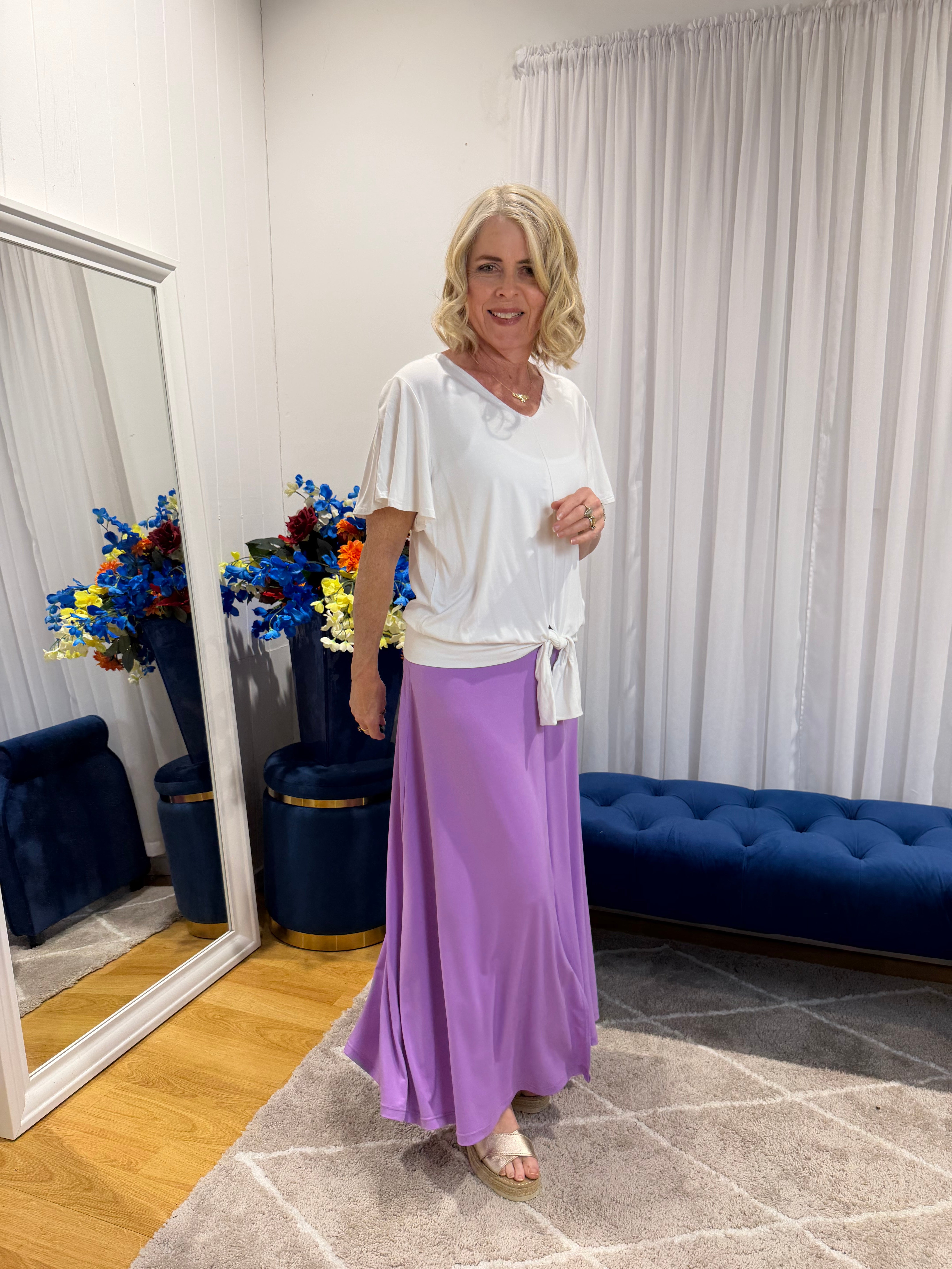 Woman wearing white top and purple skirt 