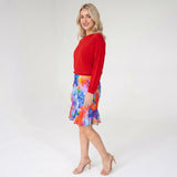 Woman wearing a red top and colorful skirt on a white background