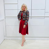 Woman wearing the Penelope dress n rich ruby red, featuring a fit-and-flare, knee length, slihouette, full length sleeves, and a cut out neckline. With embroidered silk bolero Selena Jacket.