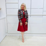 Woman wearing the Penelope dress n rich ruby red, featuring a fit-and-flare, knee length, slihouette, full length sleeves, and a cut out neckline. With embroidered silk bolero Selena Jacket. 