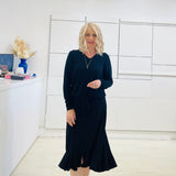 Relaxed fit, black bamboo, v neckline, long sleeve, tie front detail, dressy top. Worn with midi length skirt with slight hemline ruffle in black.
