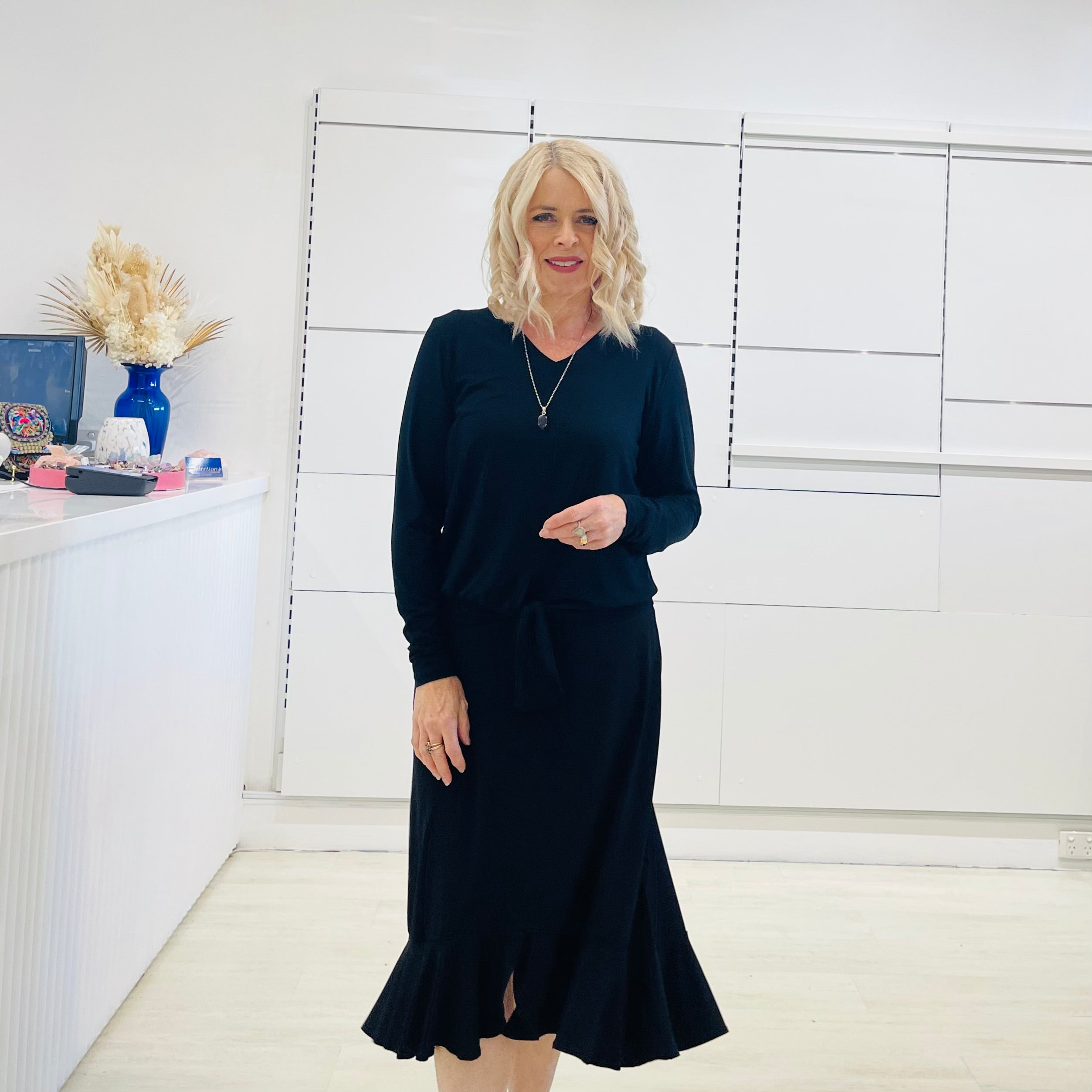 Relaxed fit, black bamboo, v neckline, long sleeve, tie front detail, dressy top. Worn with midi length skirt with slight hemline ruffle in black.