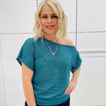 Stunning off the shoulder emerald green top with delicate shimmer. Flattering relaxed fit cut with stretch waistband for style and fit. Worn with black stretch skirt with asymmetrical hemline small ruffle detail.