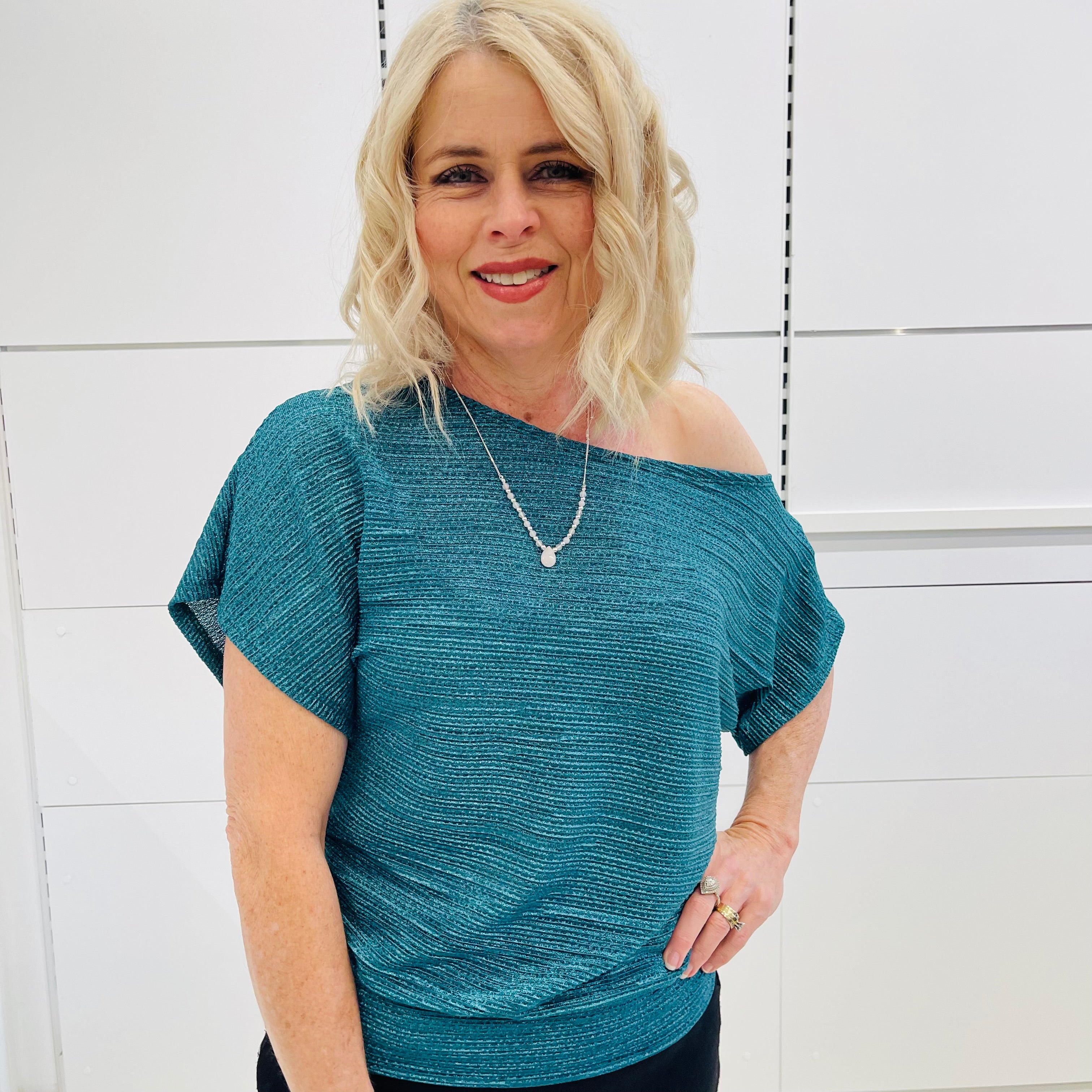 Stunning off the shoulder emerald green top with delicate shimmer. Flattering relaxed fit cut with stretch waistband for style and fit. Worn with black stretch skirt with asymmetrical hemline small ruffle detail.