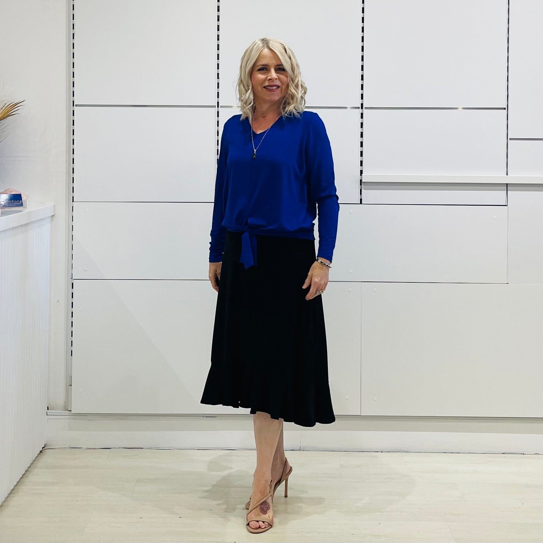 Relaxed fit, cobalt blue bamboo, v neckline, long sleeve, tie front detail, dressy top. Worn with midi length skirt with slight hemline ruffle in black.