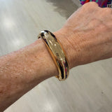 Gold bracelet on a wrist with a neutral background