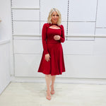 Woman wearing the Penelope dress n rich ruby red, featuring a fit-and-flare, knee length, slihouette, full length sleeves, and a cut out neckline.