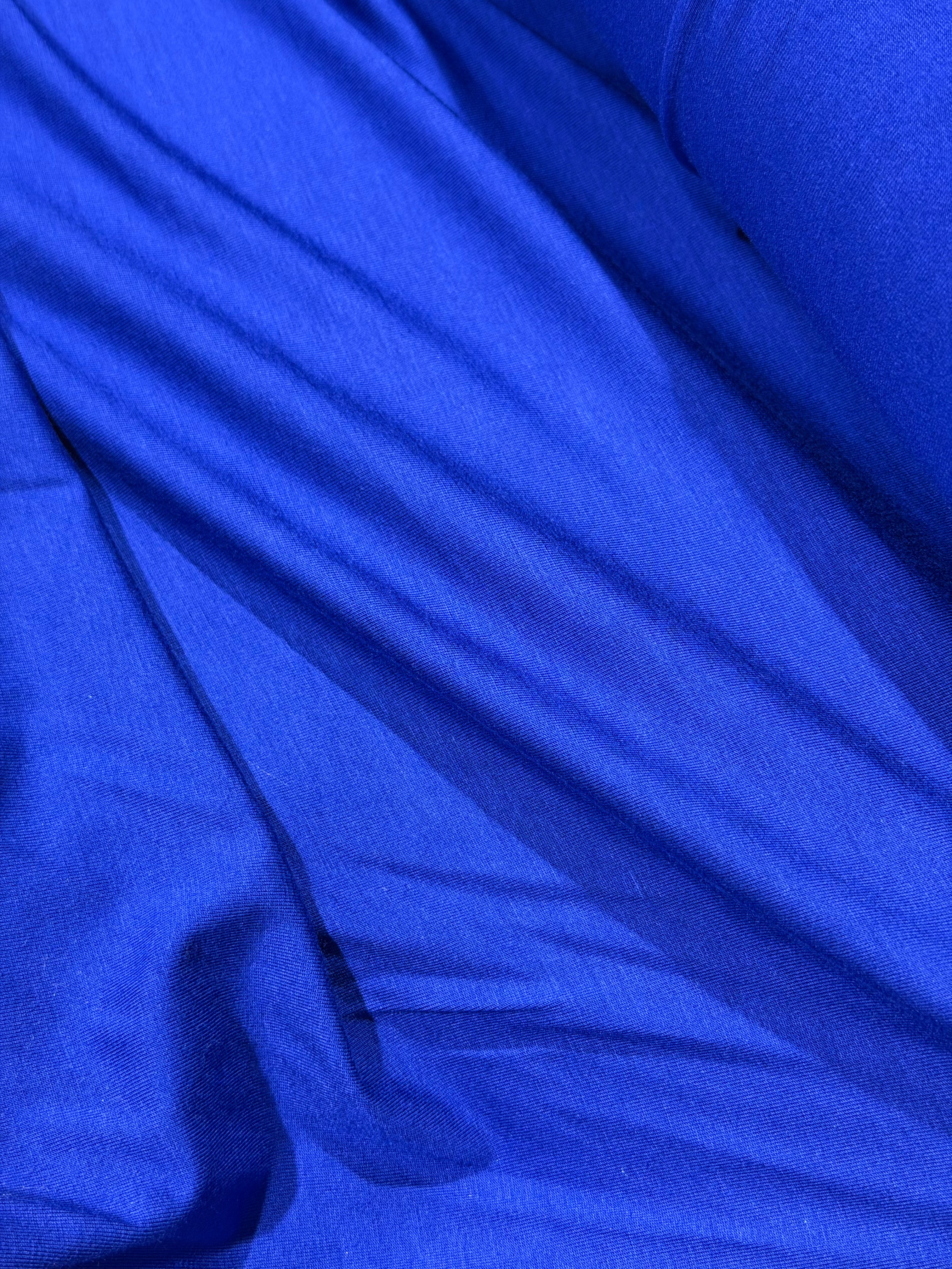 A close-up of draped royal blue fabric with soft folds and a smooth texture.