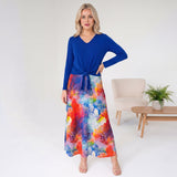 Woman wearing a blue top and colorful skirt in a minimalistic room.