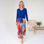 Woman wearing a blue top and colorful skirt in a minimalistic room.