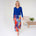 Woman wearing a blue top and colorful skirt in a minimalistic room.