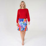 Woman wearing a red top and colorful skirt on a white background
