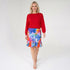Woman wearing a red top and colorful skirt on a white background