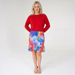 Woman wearing a red top and colorful skirt on a white background