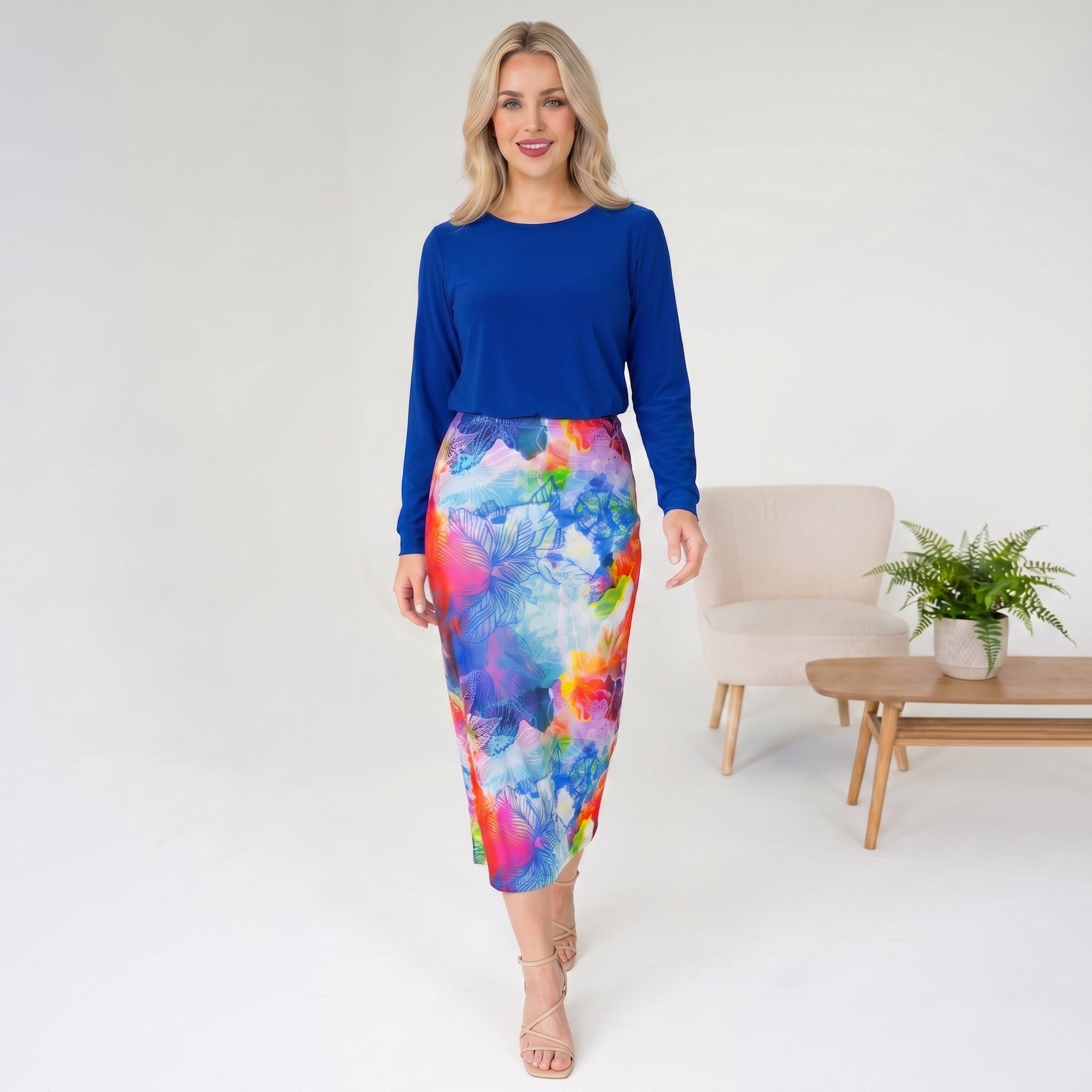 Woman wearing a blue top and colorful skirt in a minimalistic room.