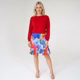 Woman wearing a red top and colorful skirt on a white background