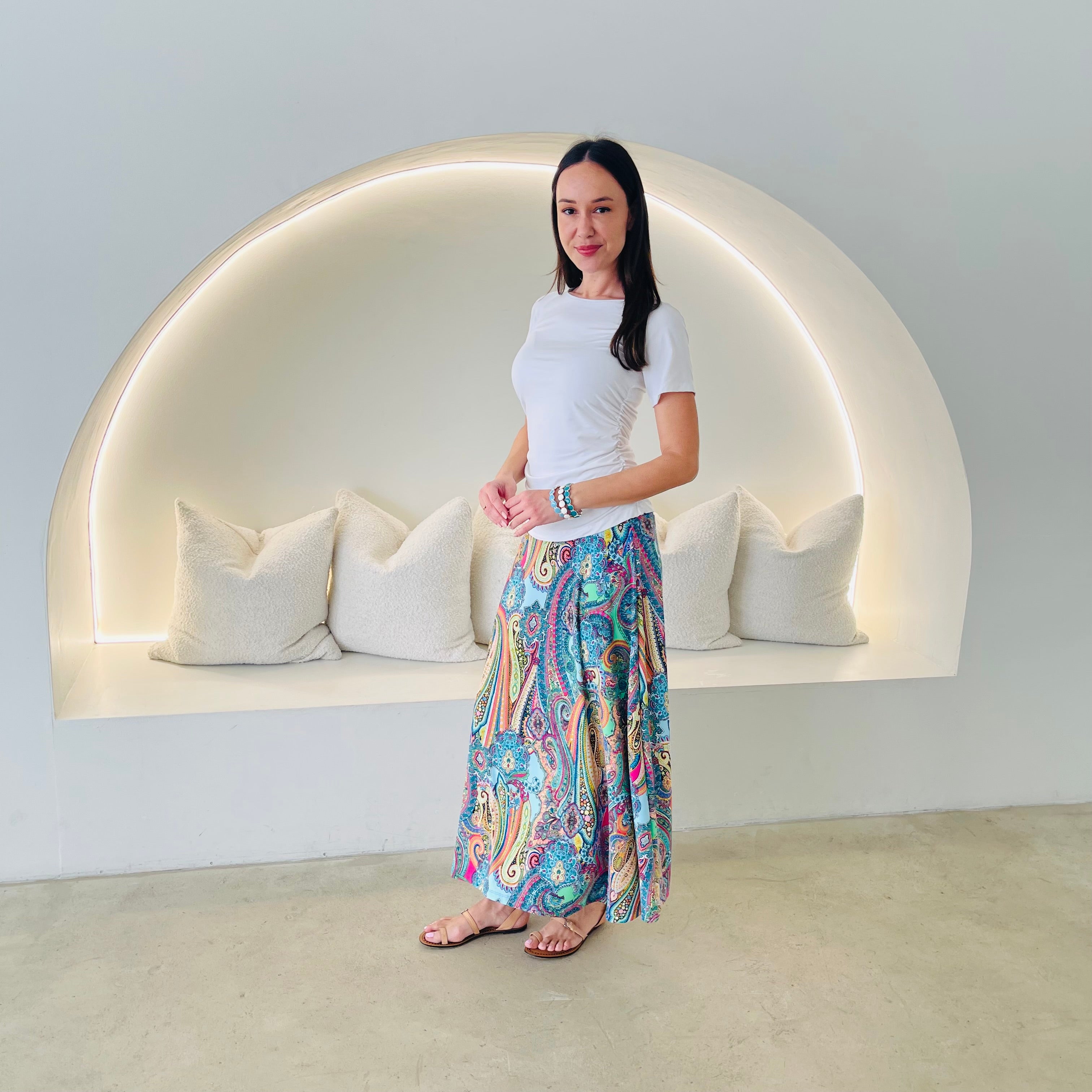 Woman standing in front of a modern wall with a built-in bench and pillows.